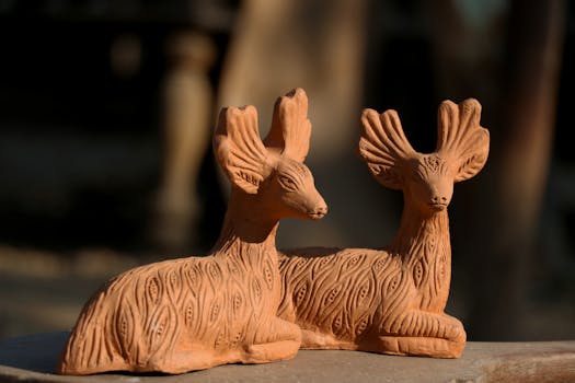 Detailed close-up of two intricately carved clay deer sculptures under natural light.